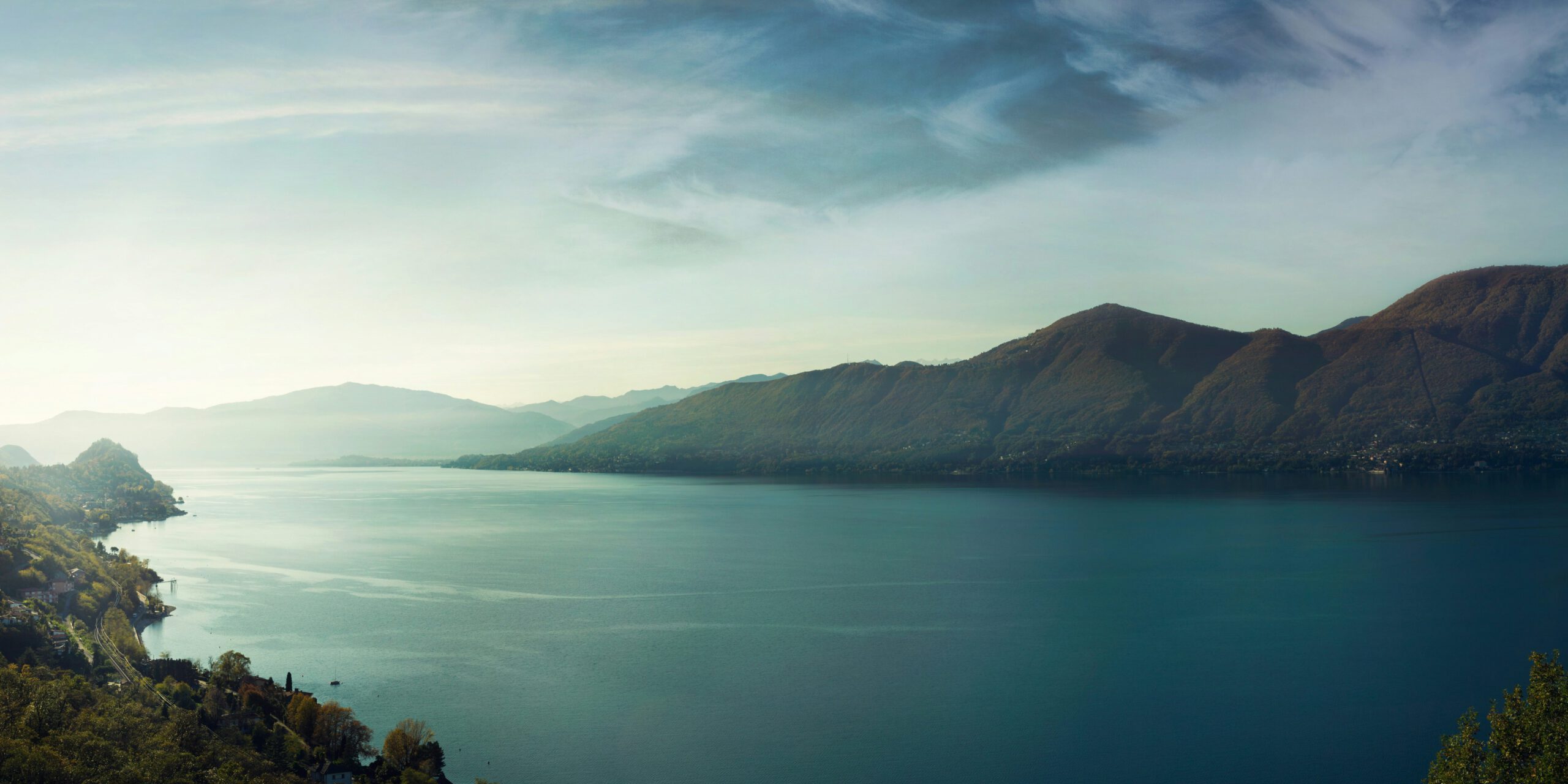 Panoramic view of a lake surrounded by mountains under a partly cloudy sky